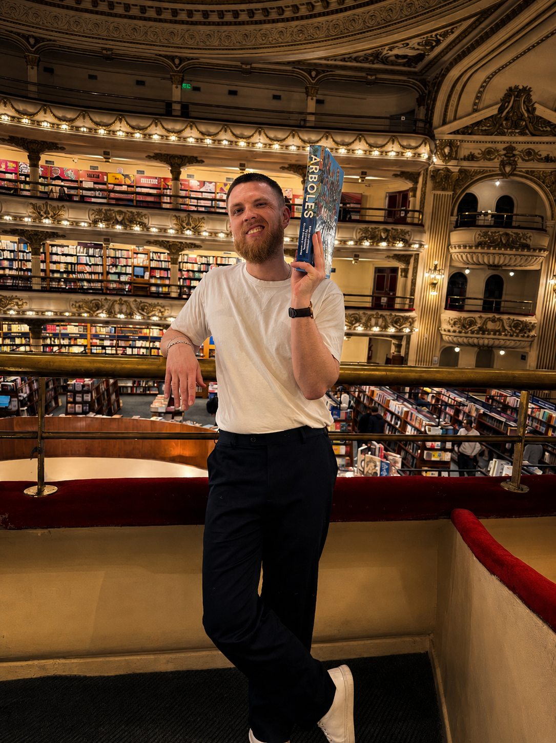 The Bad Digital Nomad holding a book in a multi-level bookstore